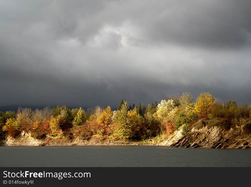 Autumn tree and bushes on background of storm cloud, low blood pressure. Autumn tree and bushes on background of storm cloud, low blood pressure