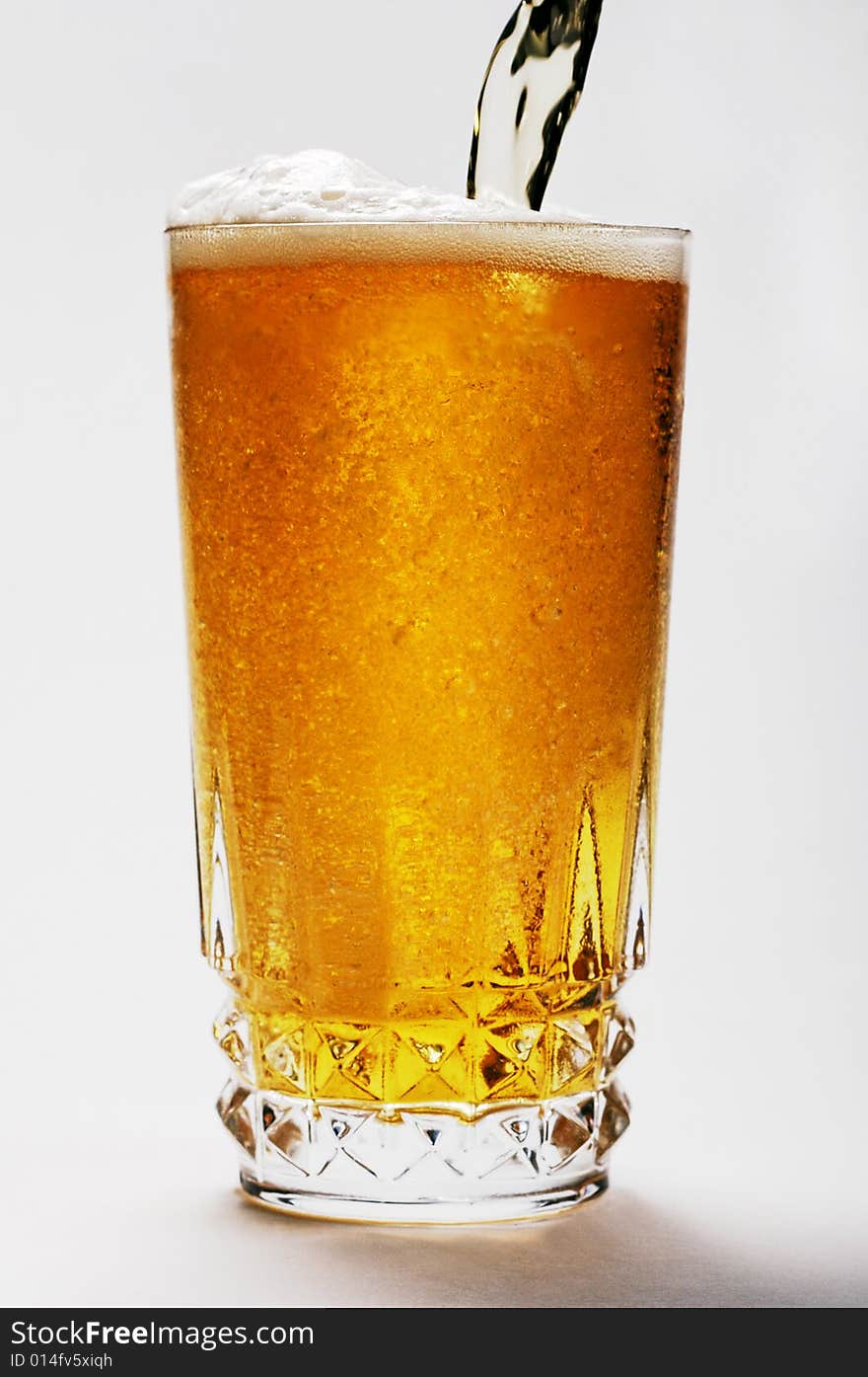 An Ice cool beer being poured in to a crystal glass with interesting froth formation. An Ice cool beer being poured in to a crystal glass with interesting froth formation.