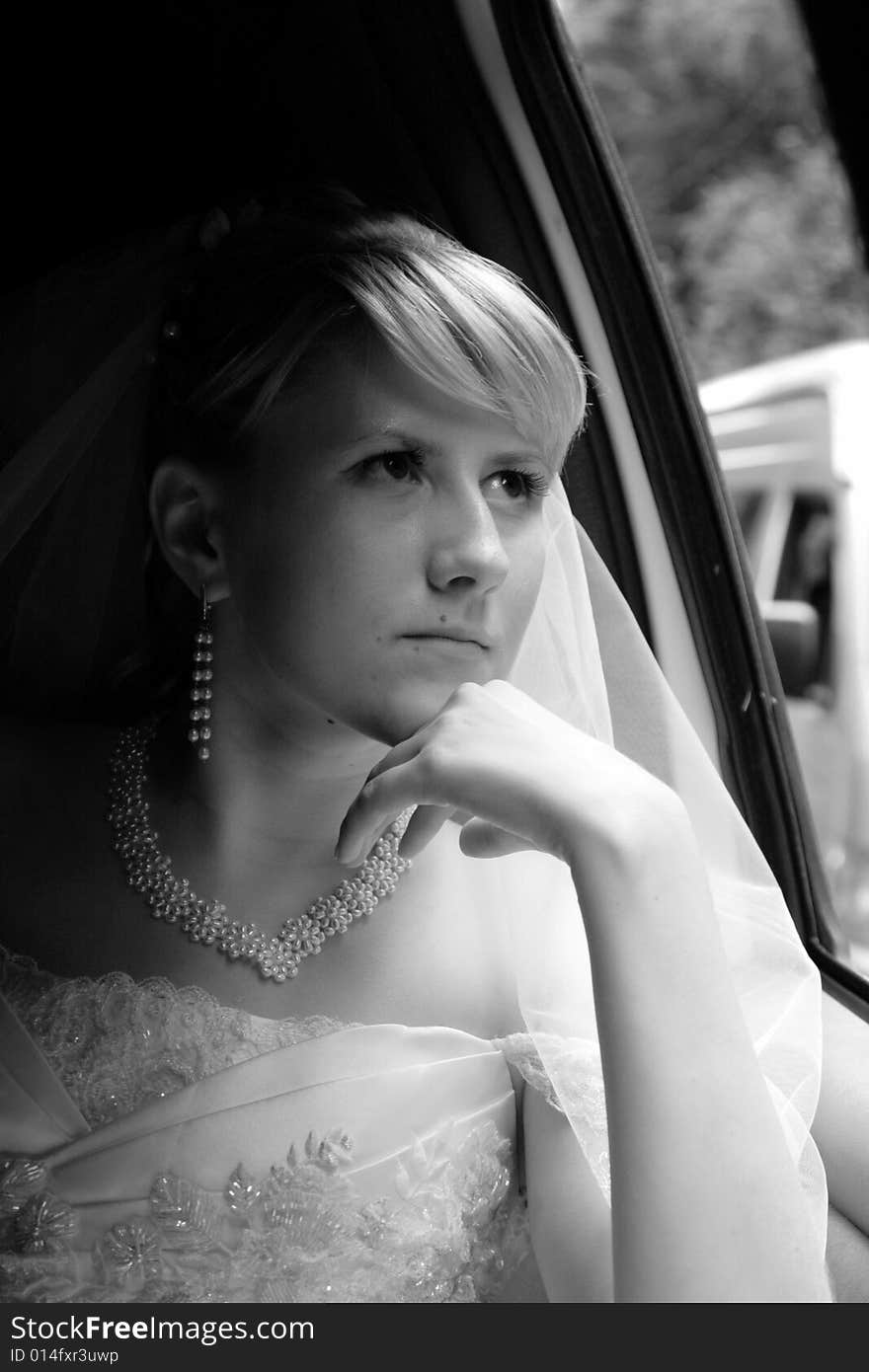 The thoughtful bride looks out of the window a limousine