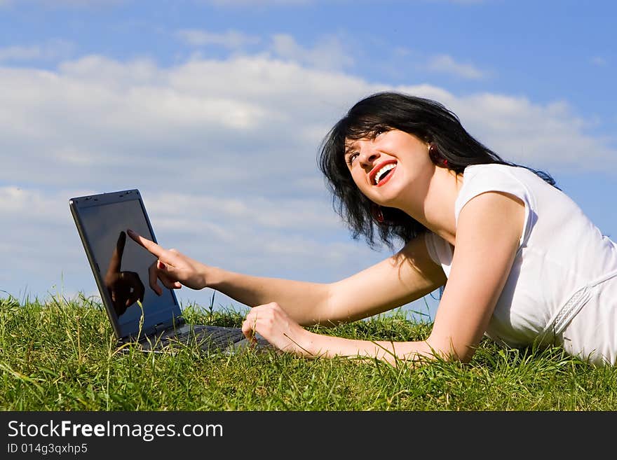 Funny woman with laptop on the green grass