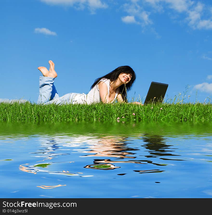 Pretty woman with laptop on the green grass