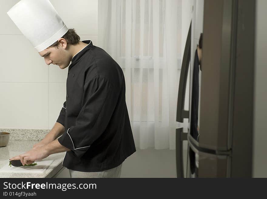 Chef's slicing parsley with a knife on a cutting board on a counter top. Vertically framed photo. Chef's slicing parsley with a knife on a cutting board on a counter top. Vertically framed photo.