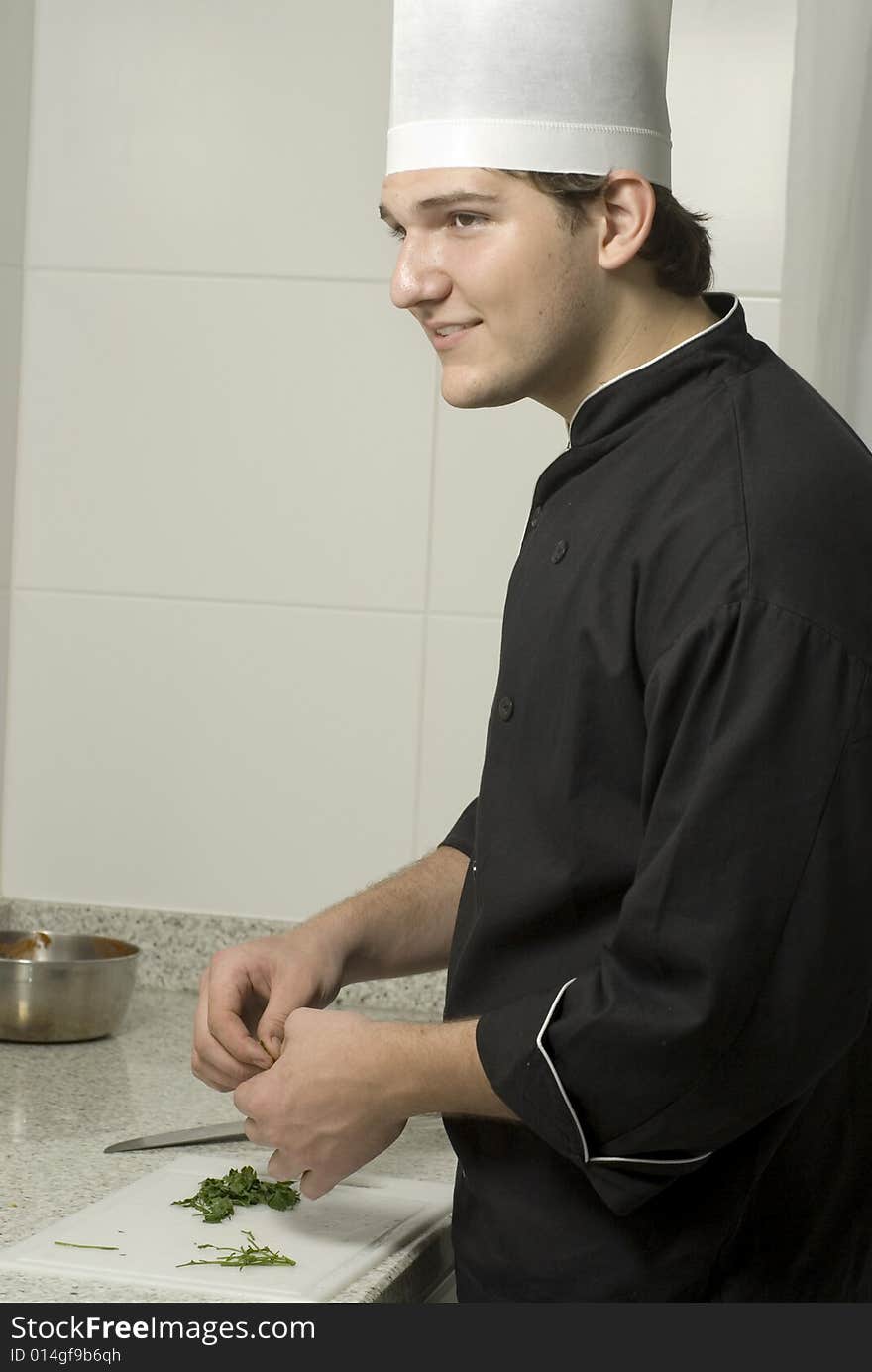 Young chef holding parsleyon a cutting board on a counter top. Vertically framed photo. Young chef holding parsleyon a cutting board on a counter top. Vertically framed photo.