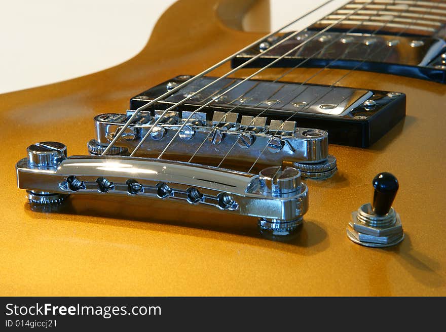 A closeup of a gold guitar on a white background