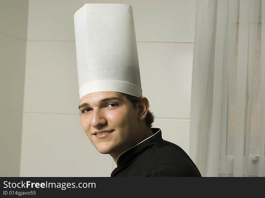 Smiling young chef in a chef's hat . Horizontally framed photo.