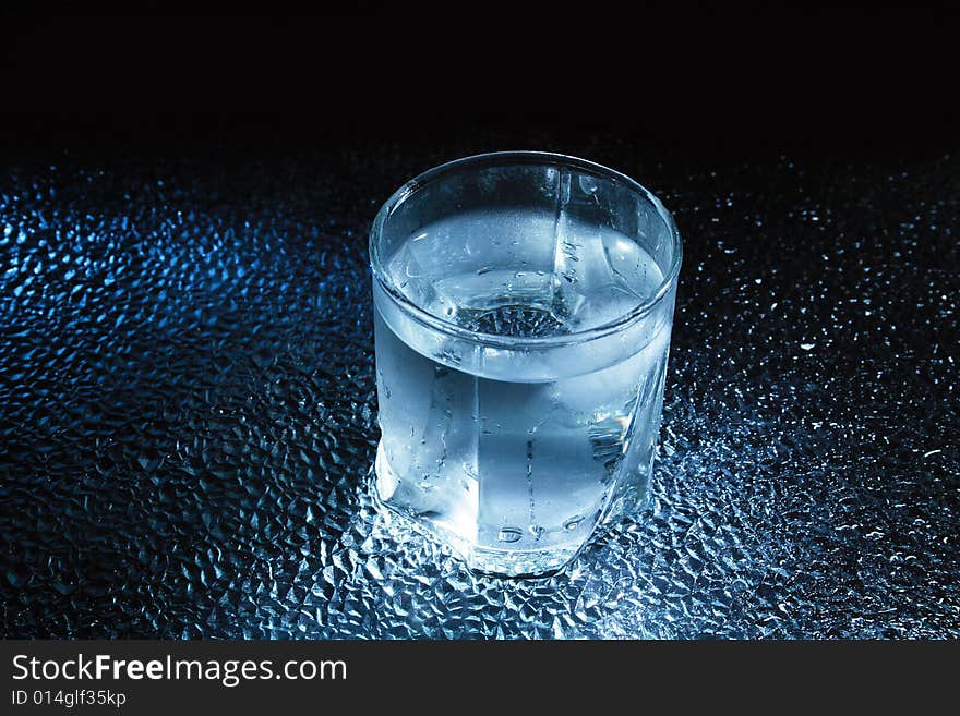 Glass of very cold water standing on dark background. Glass of very cold water standing on dark background