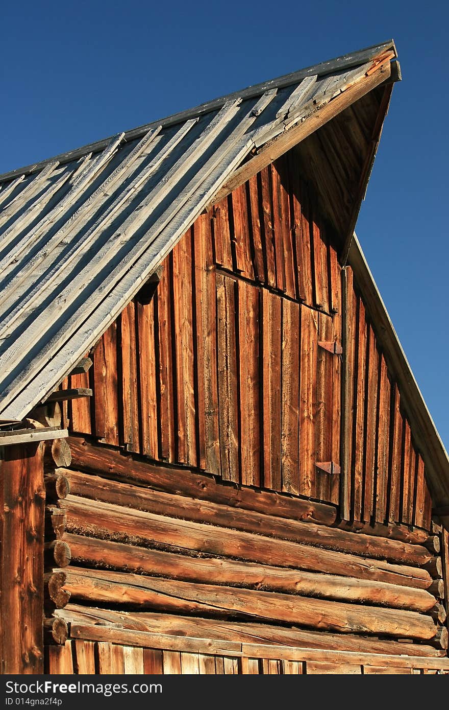 Close-up of peaked gable and side of old log barn construction. Close-up of peaked gable and side of old log barn construction