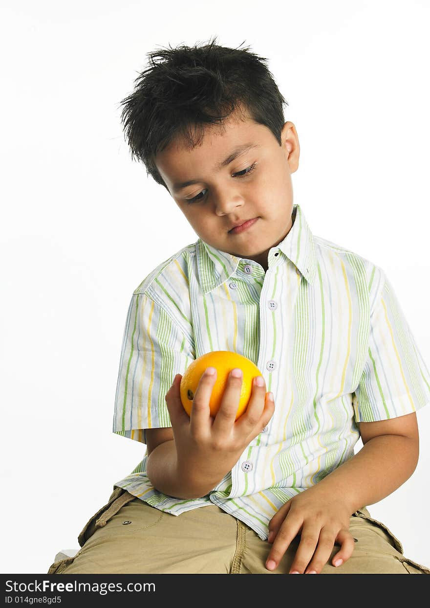 Asian boy of indian origin looking at an orange. Asian boy of indian origin looking at an orange