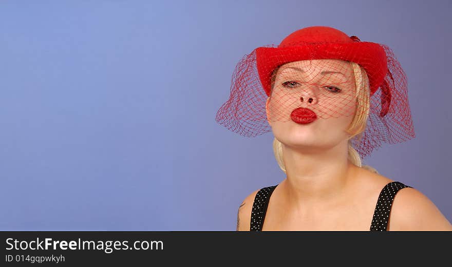 Gorgeous fifties style pinup blond girl in red hat blowing a kiss with space for text. Gorgeous fifties style pinup blond girl in red hat blowing a kiss with space for text