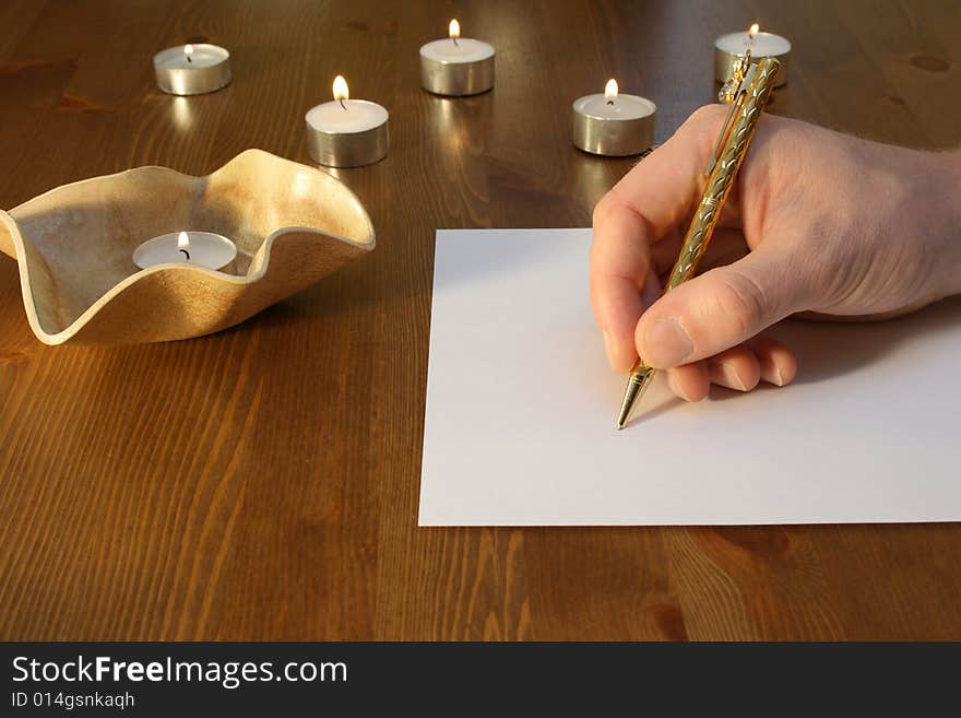 Hand wiriting with golden pen with candles. Hand wiriting with golden pen with candles