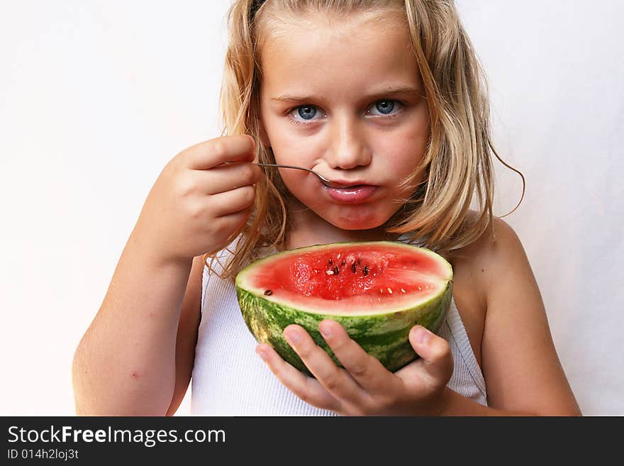 The boy with blond hair is eating melon. The boy with blond hair is eating melon.