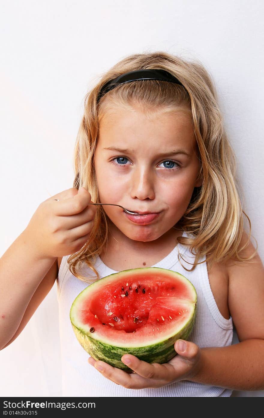 The boy with blond hair is eating melon. The boy with blond hair is eating melon.