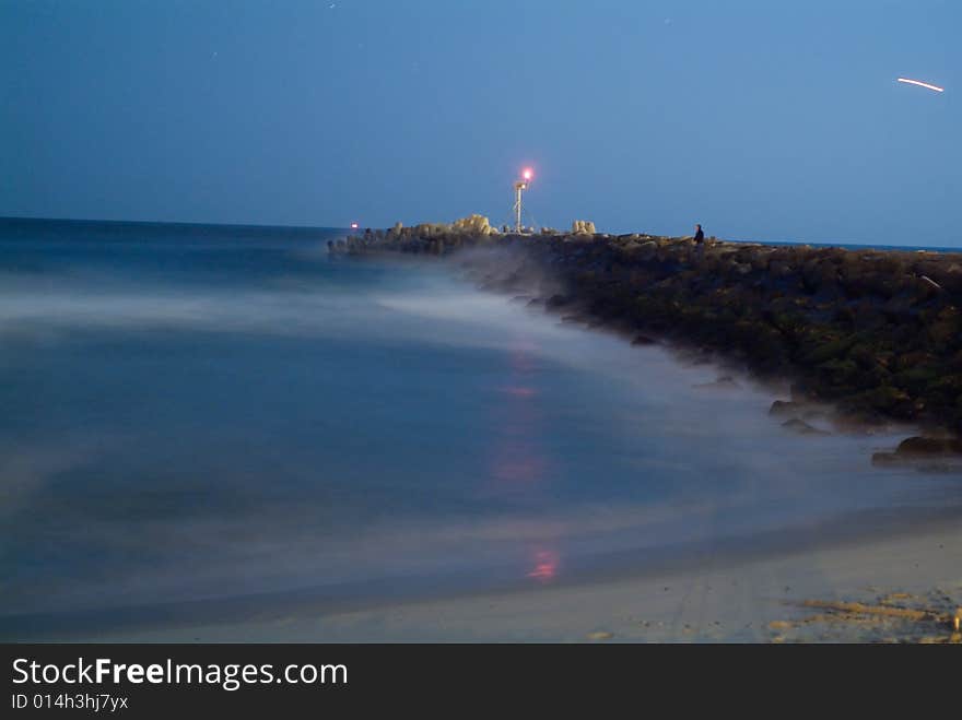 Ocean at night with long exposure showing inlet jetty. Ocean at night with long exposure showing inlet jetty