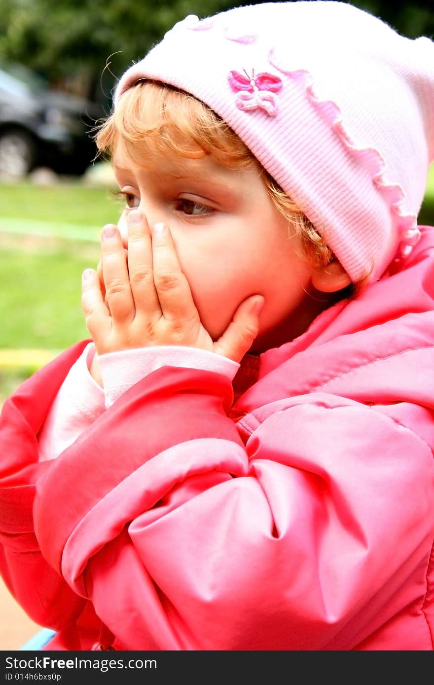 A little girl closes a mouth with her hands