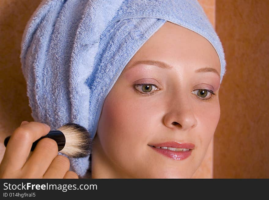 Beautiful young woman doing make-up in the bathroom.