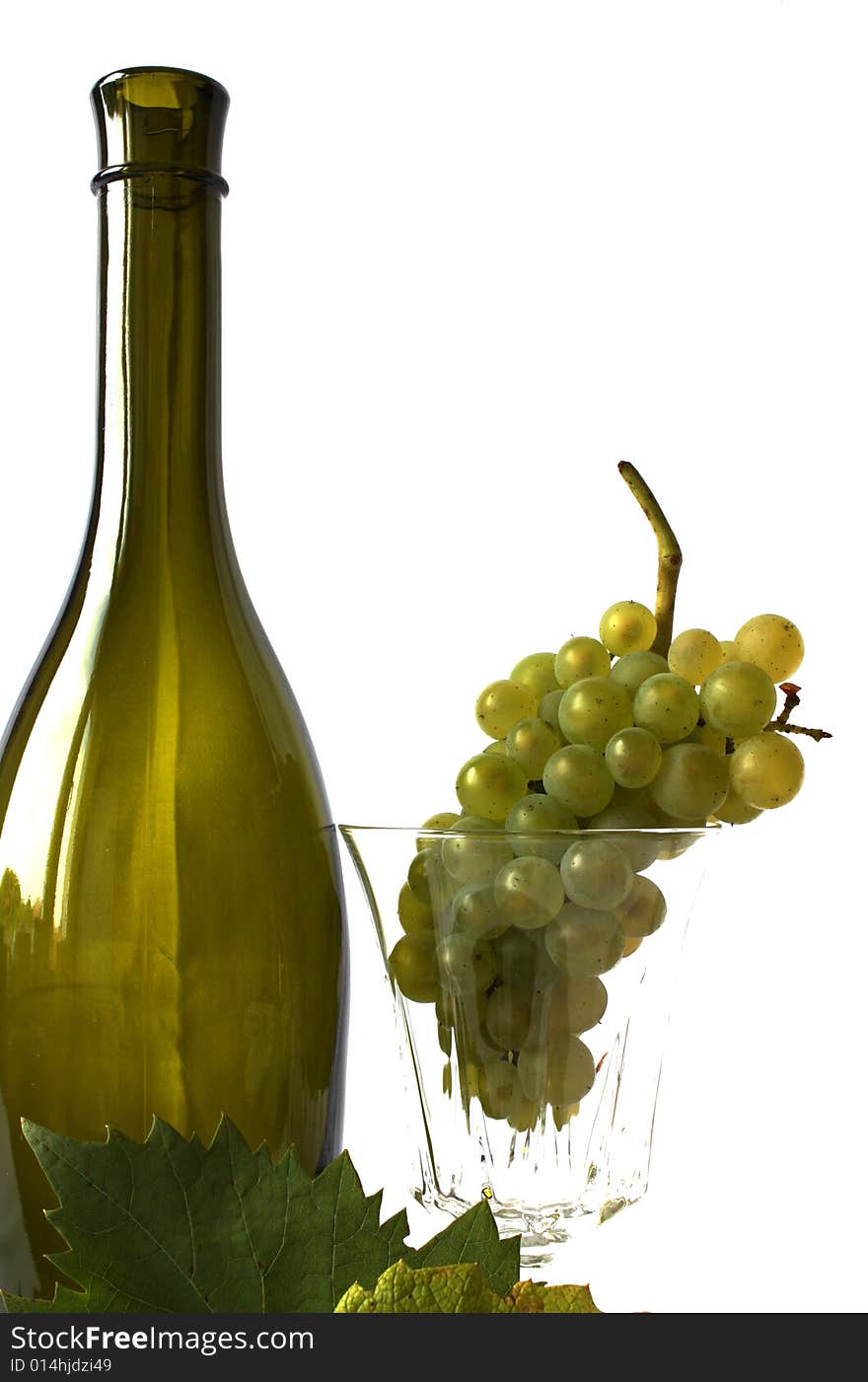 Grapes - fruits and leaves on a white backgroung with an empty glass and green bottle. Grapes - fruits and leaves on a white backgroung with an empty glass and green bottle.