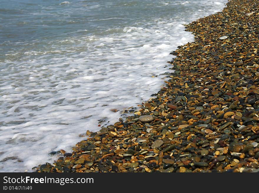 Sea-wave and shingle coastline on a bright day