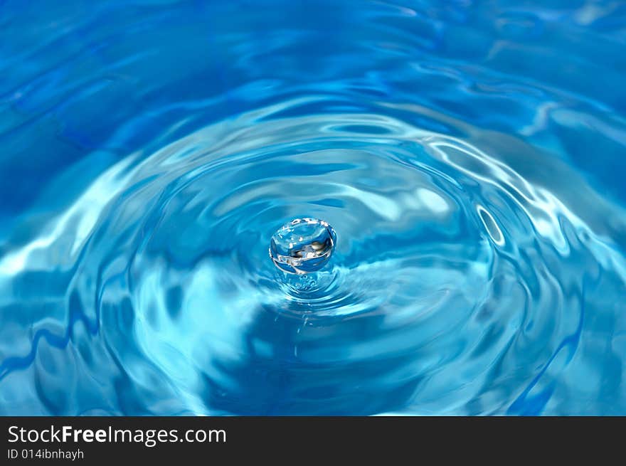 Shining waterdrop flying above rippled water surface. Shining waterdrop flying above rippled water surface