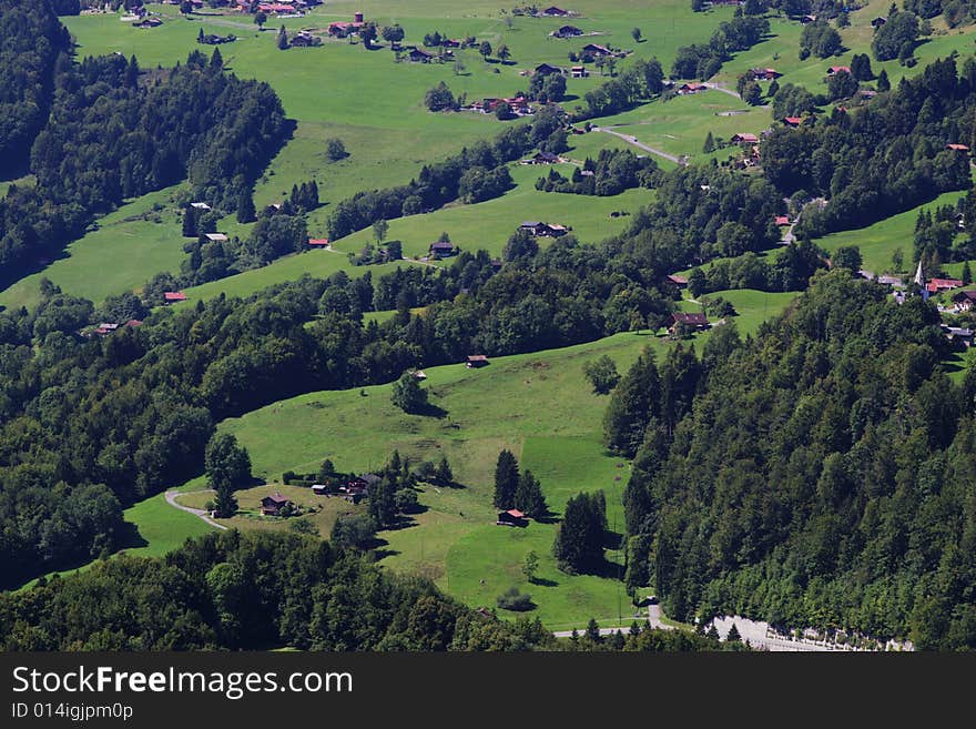 Summer rural landscape view on green Alps mountains, trees, slopes, and wooden detached houses. Alps, Switzerland, europe. Summer rural landscape view on green Alps mountains, trees, slopes, and wooden detached houses. Alps, Switzerland, europe.