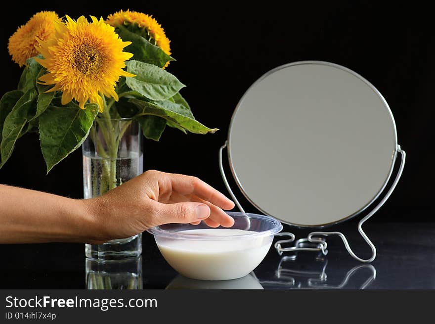 Objects on the toilet table and the hand of woman which uses the cream