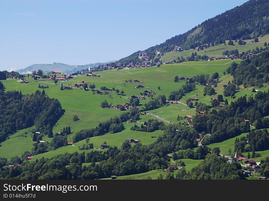 Summer rural landscape view on green Alps mountains, trees, slopes, and wooden detached houses. Alps, Switzerland, europe. Summer rural landscape view on green Alps mountains, trees, slopes, and wooden detached houses. Alps, Switzerland, europe.