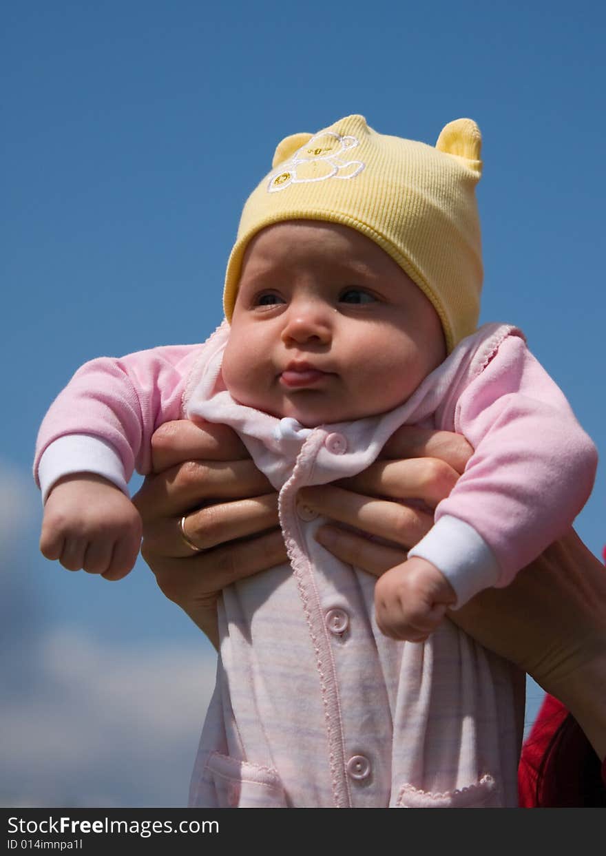 Little baby on mother's hands on blue sky background