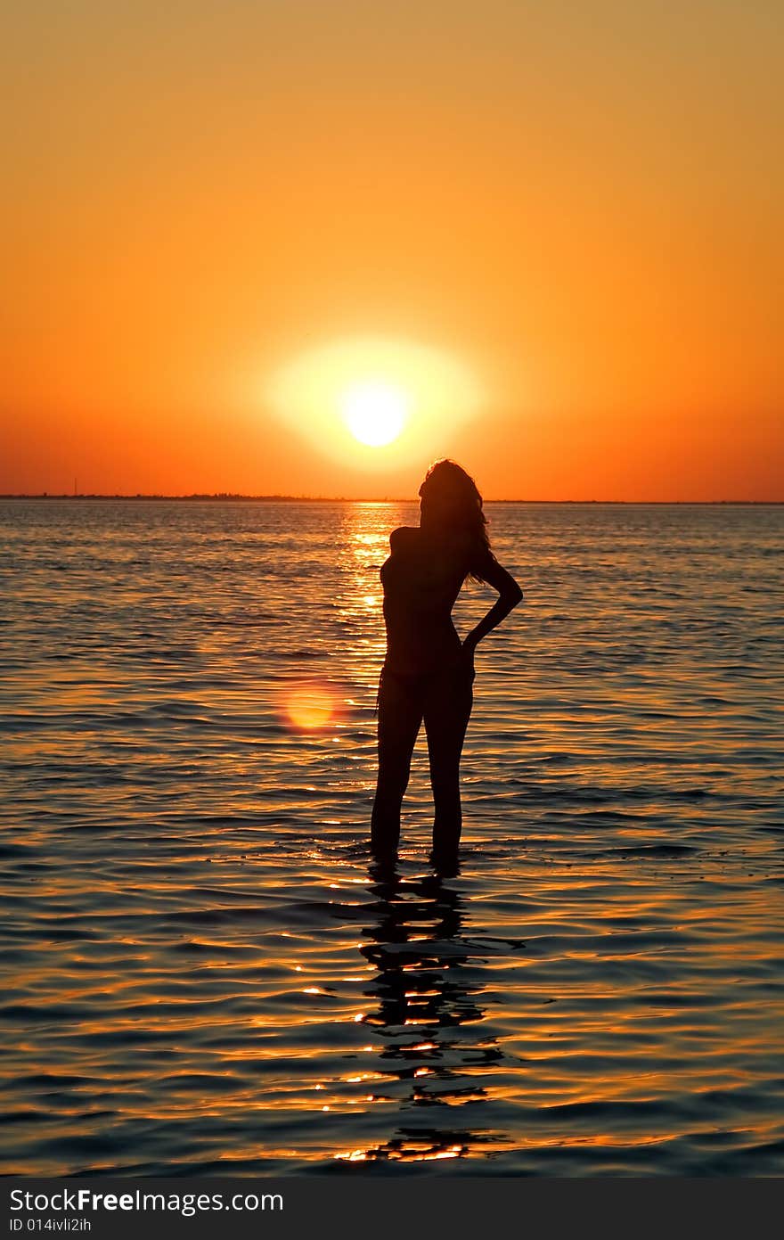 Silhouette of the young woman on a gulf on a sunset