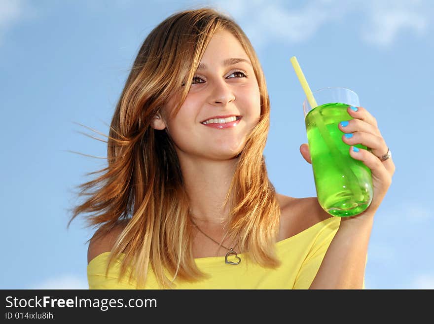 A wonderful young girl stands on a background dark blue sky and holds in a hand glass with drink