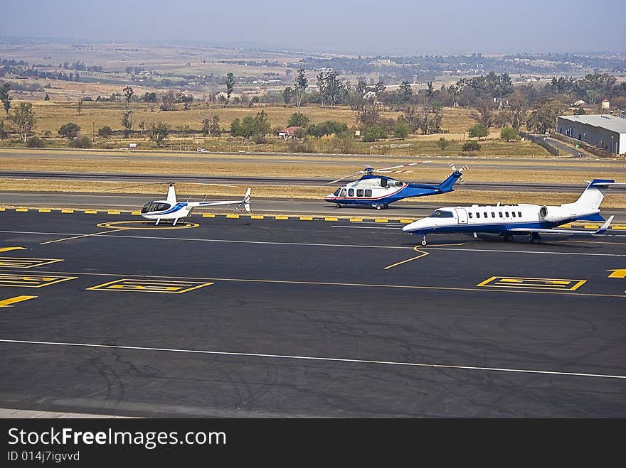 Agusta Westland AW139 Helicopter taxying down the runway, shortly after landing at Lanseria International Airport, South Africa. This model of helicopter is often preferred by business executives as their means of airport shuttle. 15-seat medium sized twin-engined helicopter. This scene shows more of the slipway, with other aircraft parked. Also visible in the background is the flat, wide open landscape. FALA. Agusta Westland AW139 Helicopter taxying down the runway, shortly after landing at Lanseria International Airport, South Africa. This model of helicopter is often preferred by business executives as their means of airport shuttle. 15-seat medium sized twin-engined helicopter. This scene shows more of the slipway, with other aircraft parked. Also visible in the background is the flat, wide open landscape. FALA