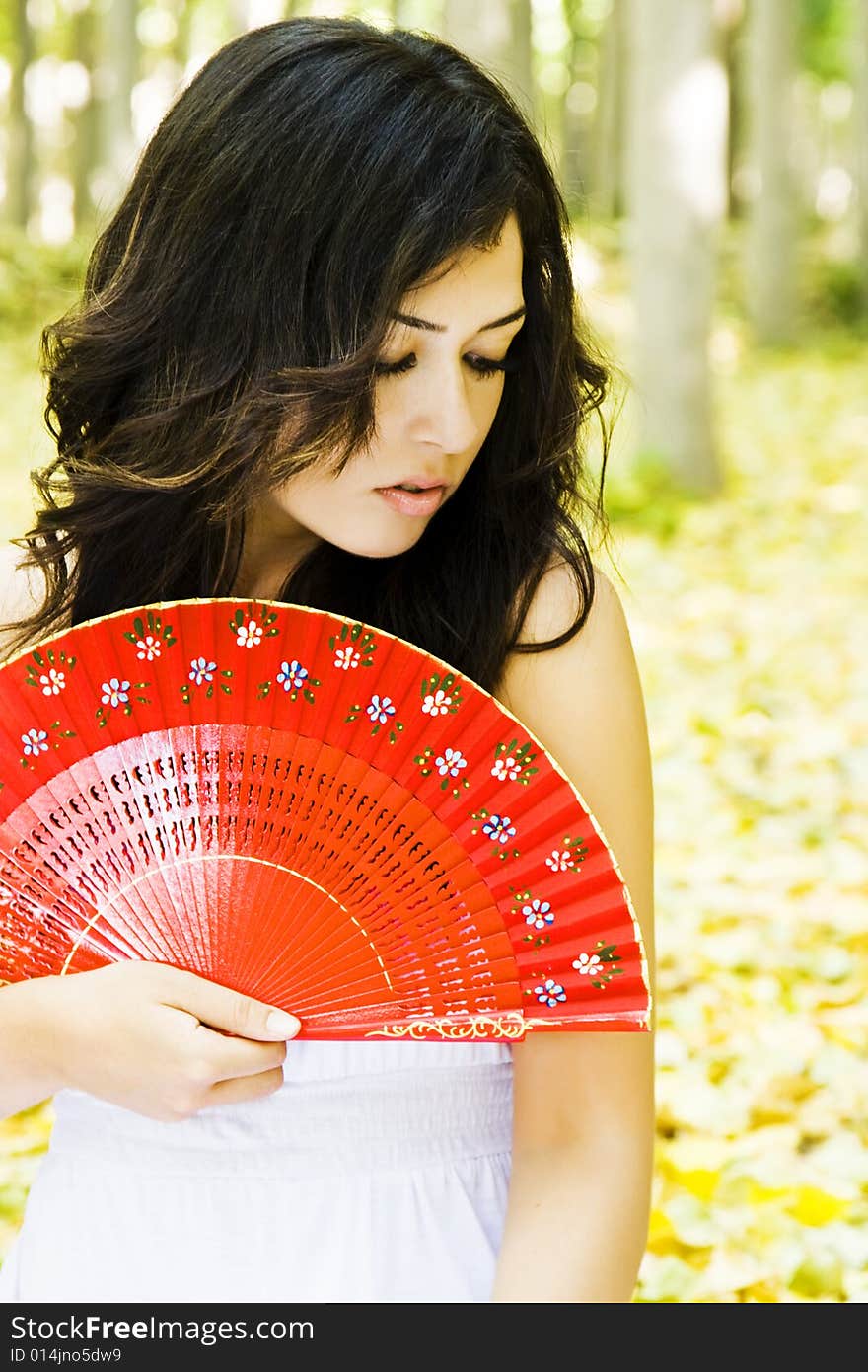 Young woman with red fan in a forest. Young woman with red fan in a forest.