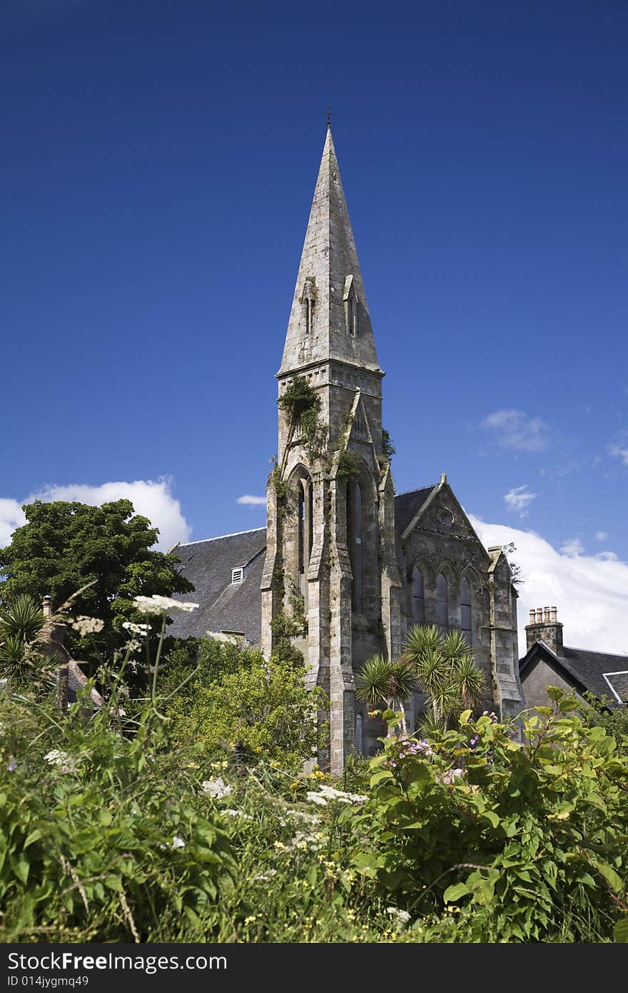 Overgrown steeple of a disused victorian church against blue sky. Overgrown steeple of a disused victorian church against blue sky