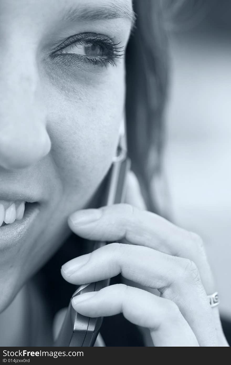 Woman smiling with cell phone up to her ear, blue toned. Woman smiling with cell phone up to her ear, blue toned