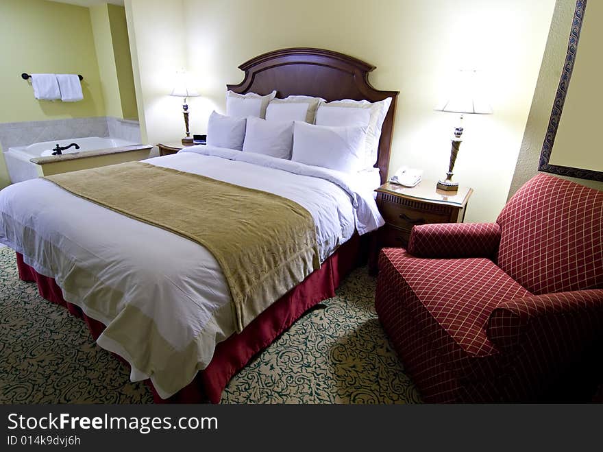 Hotel bedroom with king sized bed, chair and jacuzzi bathtub. Hotel bedroom with king sized bed, chair and jacuzzi bathtub