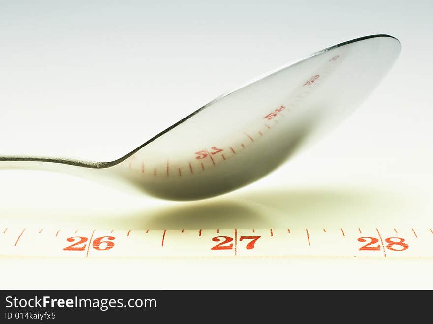 Studio shot of spoon and measuring tape against white background. Studio shot of spoon and measuring tape against white background