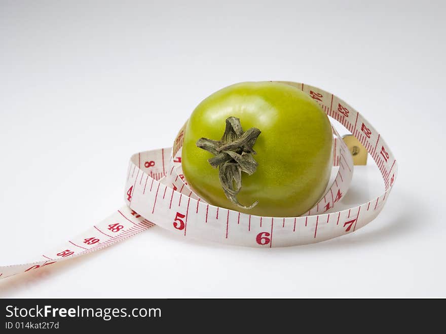 Studio shot of tomato and measuring tape against white background. Studio shot of tomato and measuring tape against white background