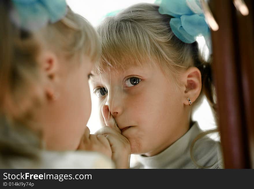 The little girl looks in the mirror. The little girl looks in the mirror