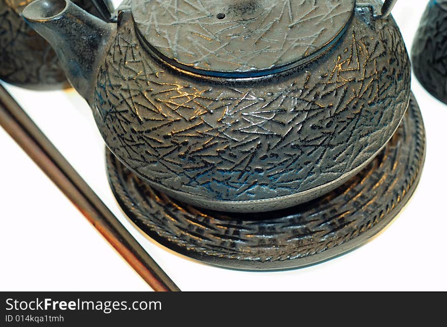 This is a shot of a Chinese tea pot, cups and chopsticks.