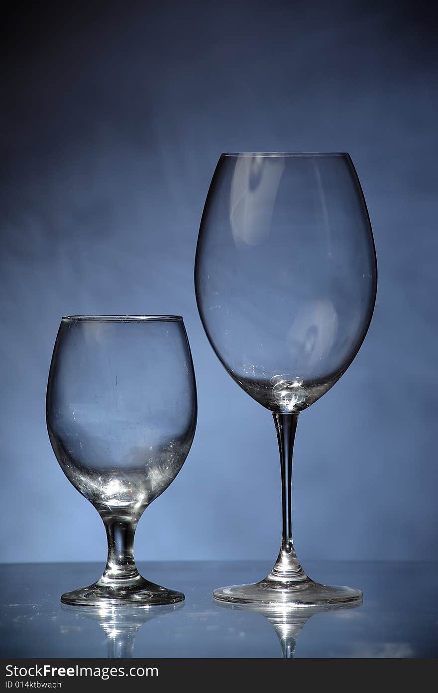 Two fine glasses standing next to each other on dirty blue background, like a tiny glass couple.