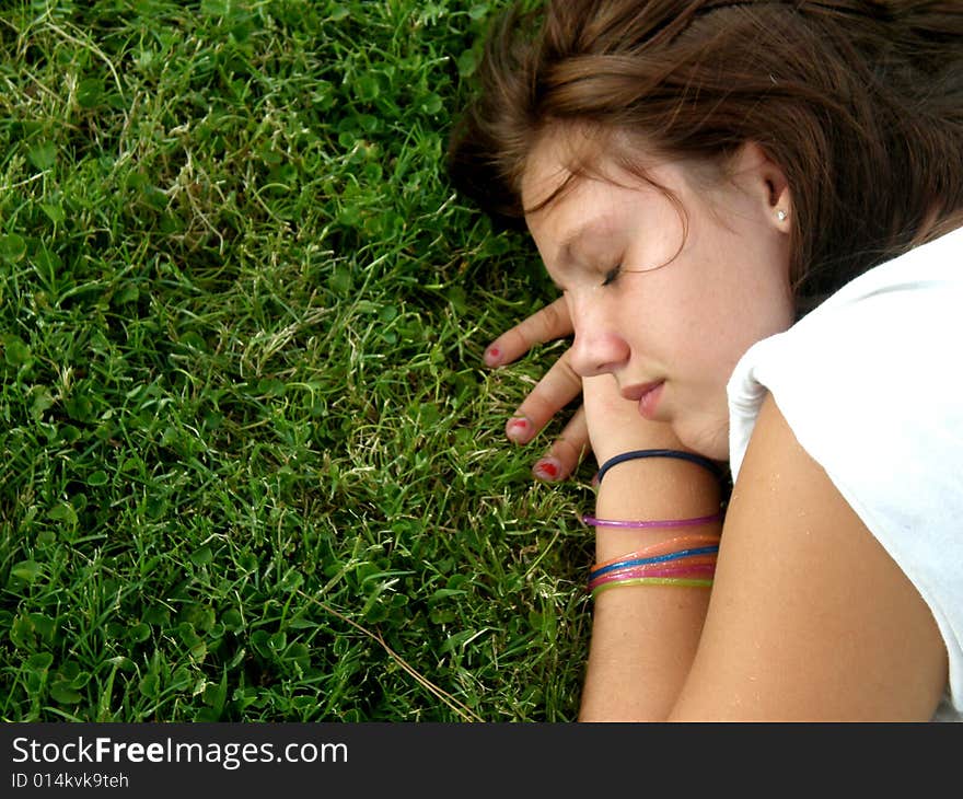 A picture of a young teen girl resting in the grass. A picture of a young teen girl resting in the grass.