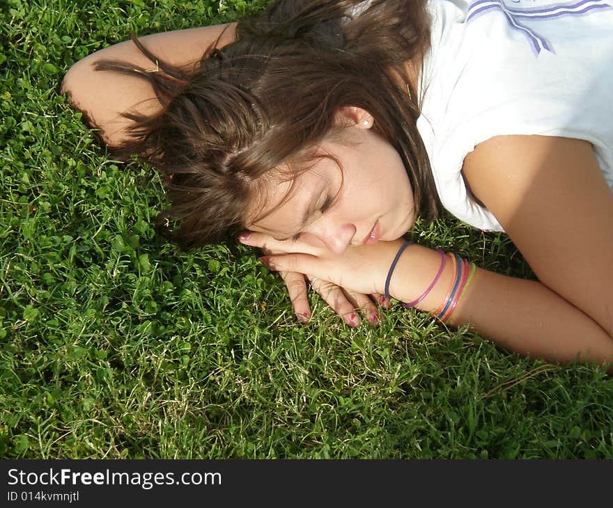 A picture of a young teen girl sleeping in the grass.