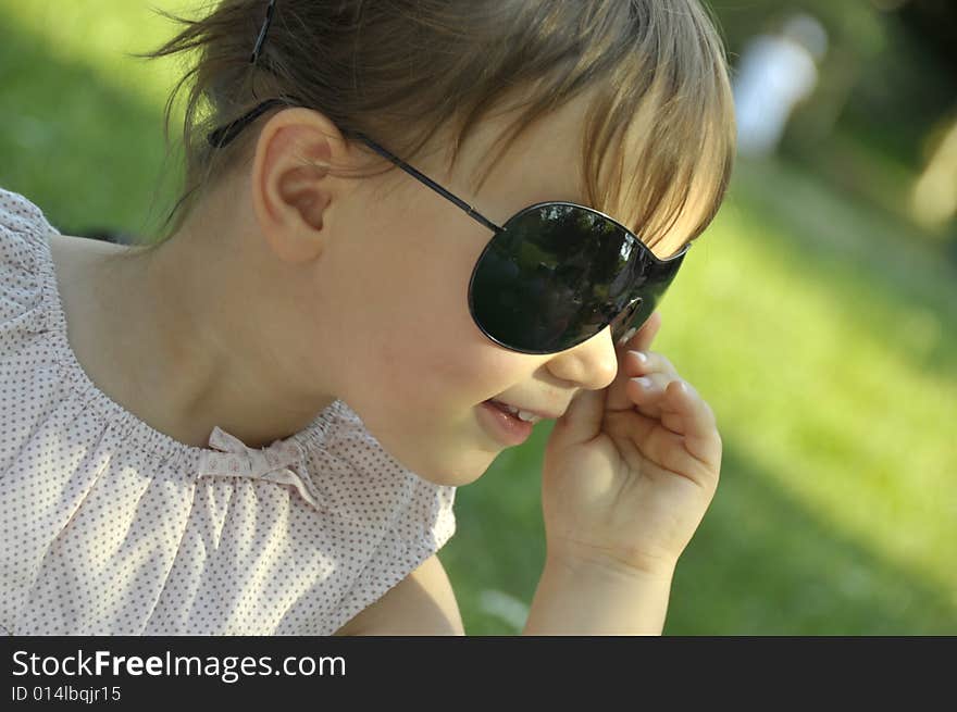 Beautiful girl in sun glasses on a background a green grass. Beautiful girl in sun glasses on a background a green grass