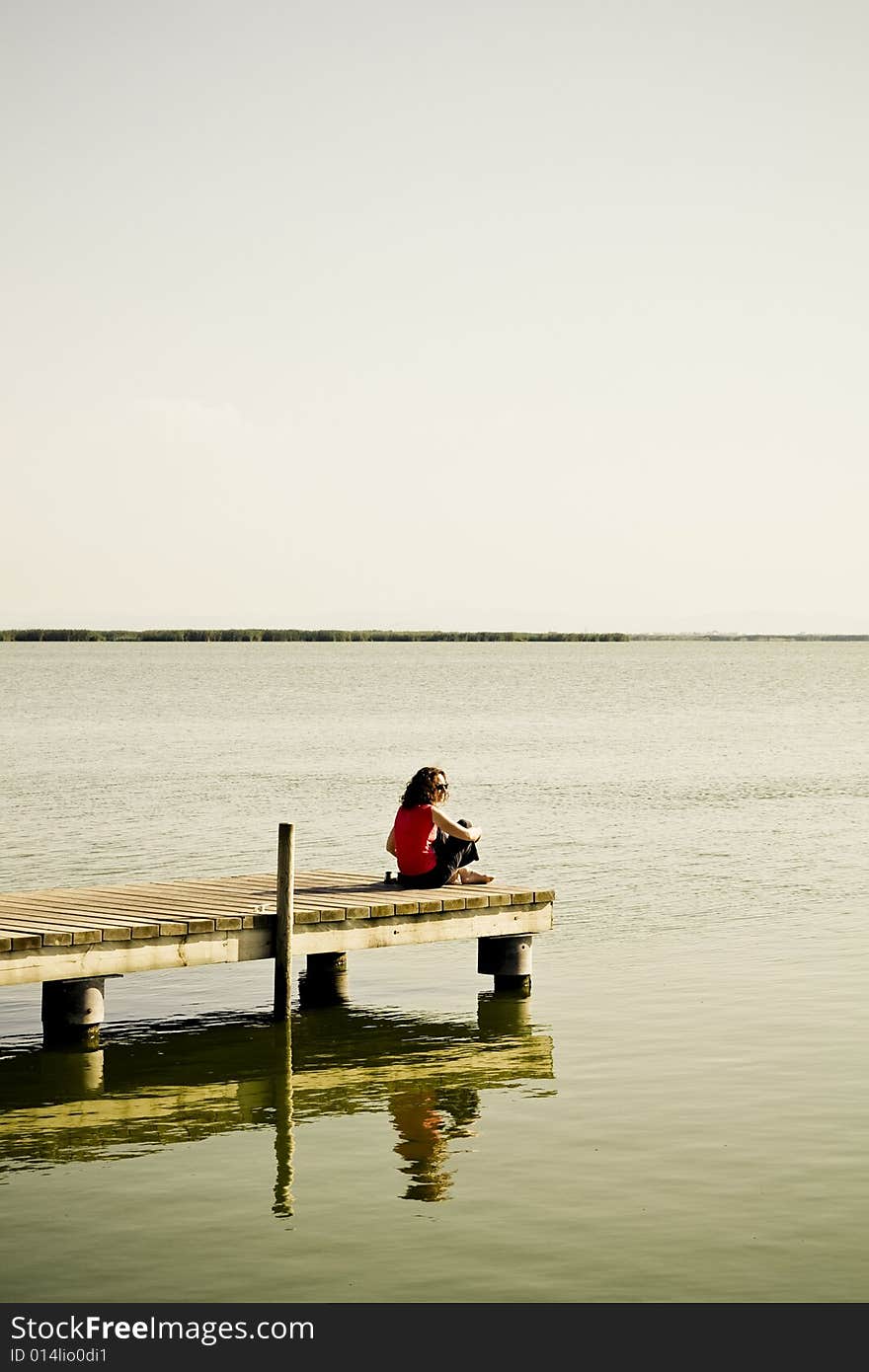 Young woman sitting in the dock of the bay. Young woman sitting in the dock of the bay