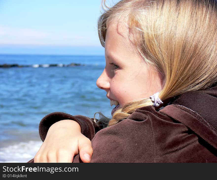 Young blond girl smiling at seaside - close up