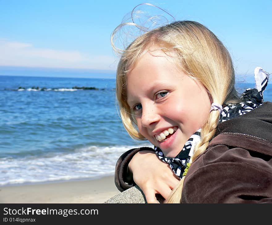 Young blond girl smiling at seaside - close up