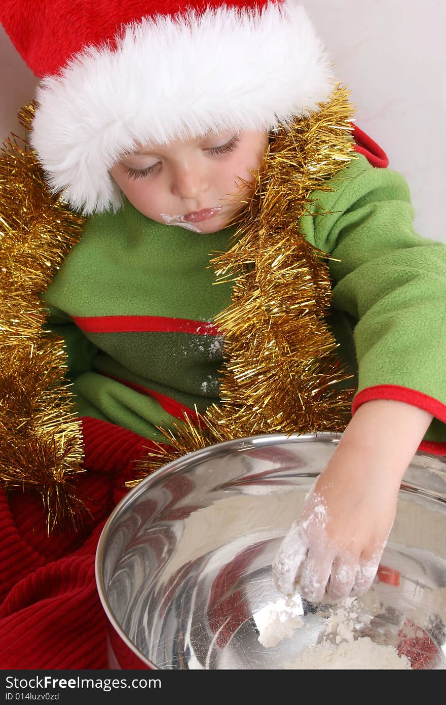 Toddler wearing a christmas hat, baking christmas cookies