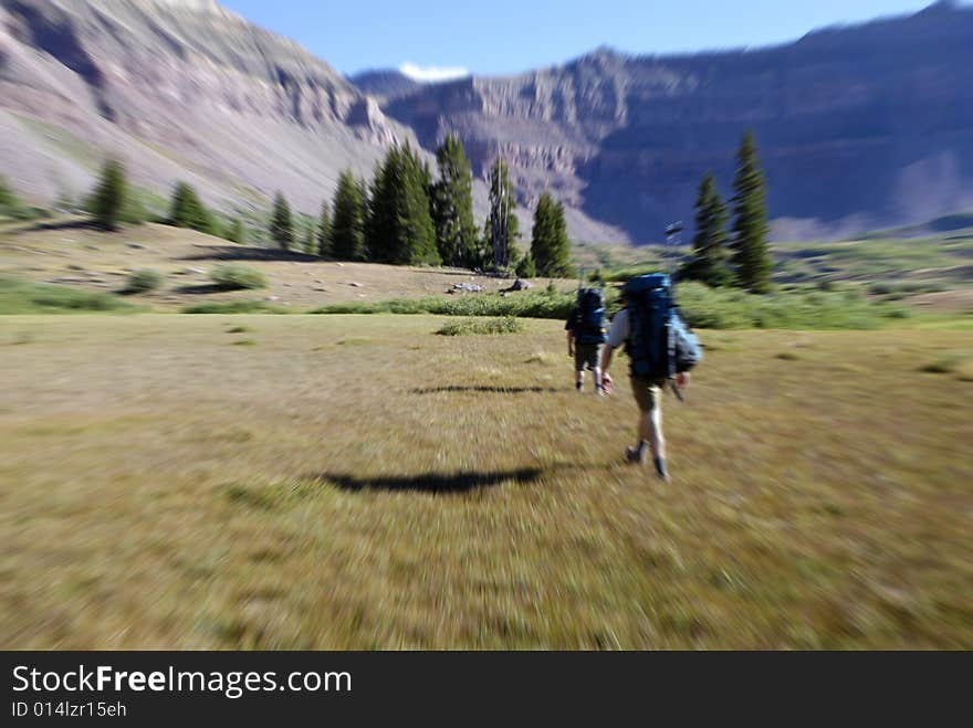 People hiking along rocky trail towards distant mountain range. People hiking along rocky trail towards distant mountain range