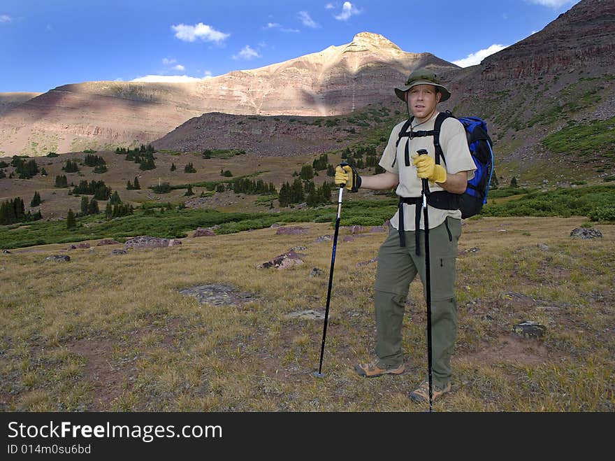 One person walking along trail with brush and mountains in background. One person walking along trail with brush and mountains in background