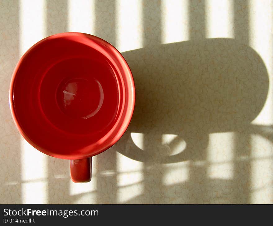 Red round cup reflects upon a table