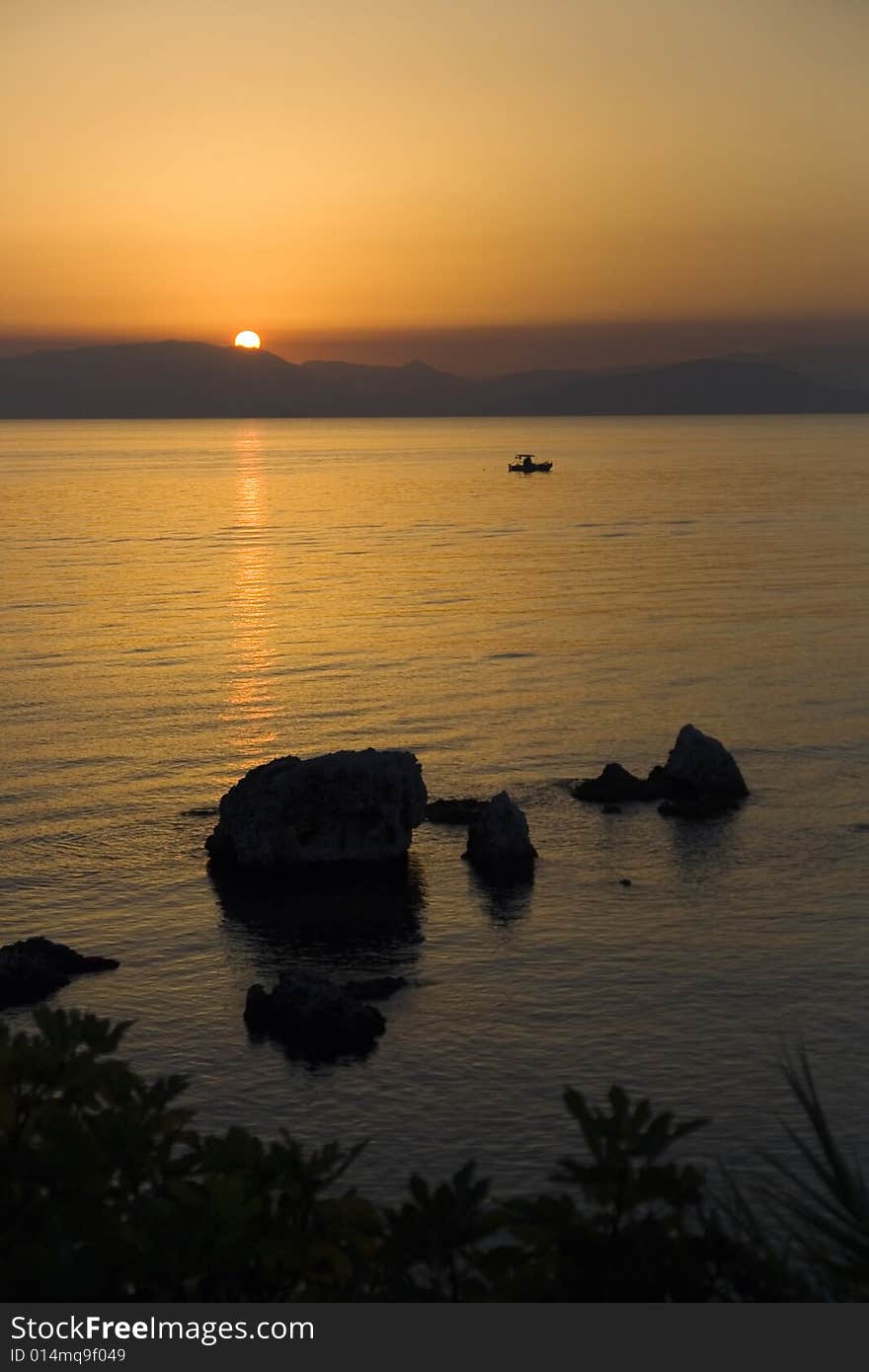 Surise over Greece seen from Corfu island with rocks in foreground. The sea is the Ionian sea. Surise over Greece seen from Corfu island with rocks in foreground. The sea is the Ionian sea.