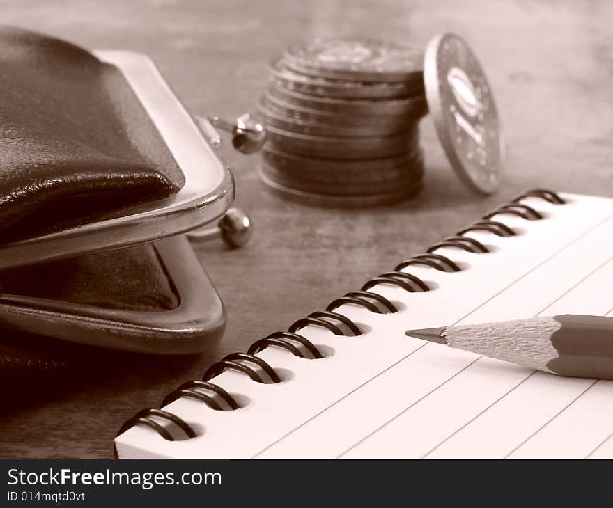 Sepia toned notepad with pencil and purse with coins stack. Sepia toned notepad with pencil and purse with coins stack